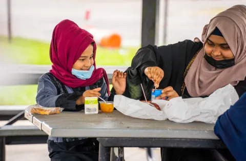 Two girls in hijabs eating a meal