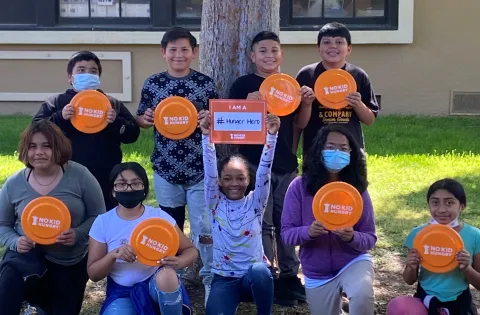 Kids holding No Kid Hungry frisbees