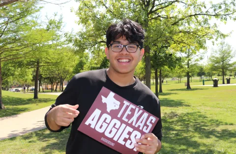 Young man holding Texas Aggies sign