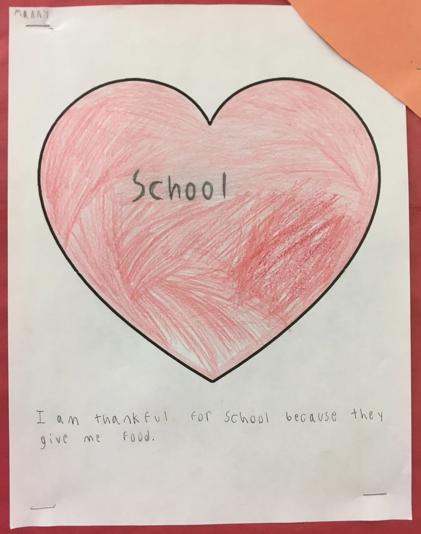 A child's illustration of a heart with the words, "I am thankful for school because they give me food."