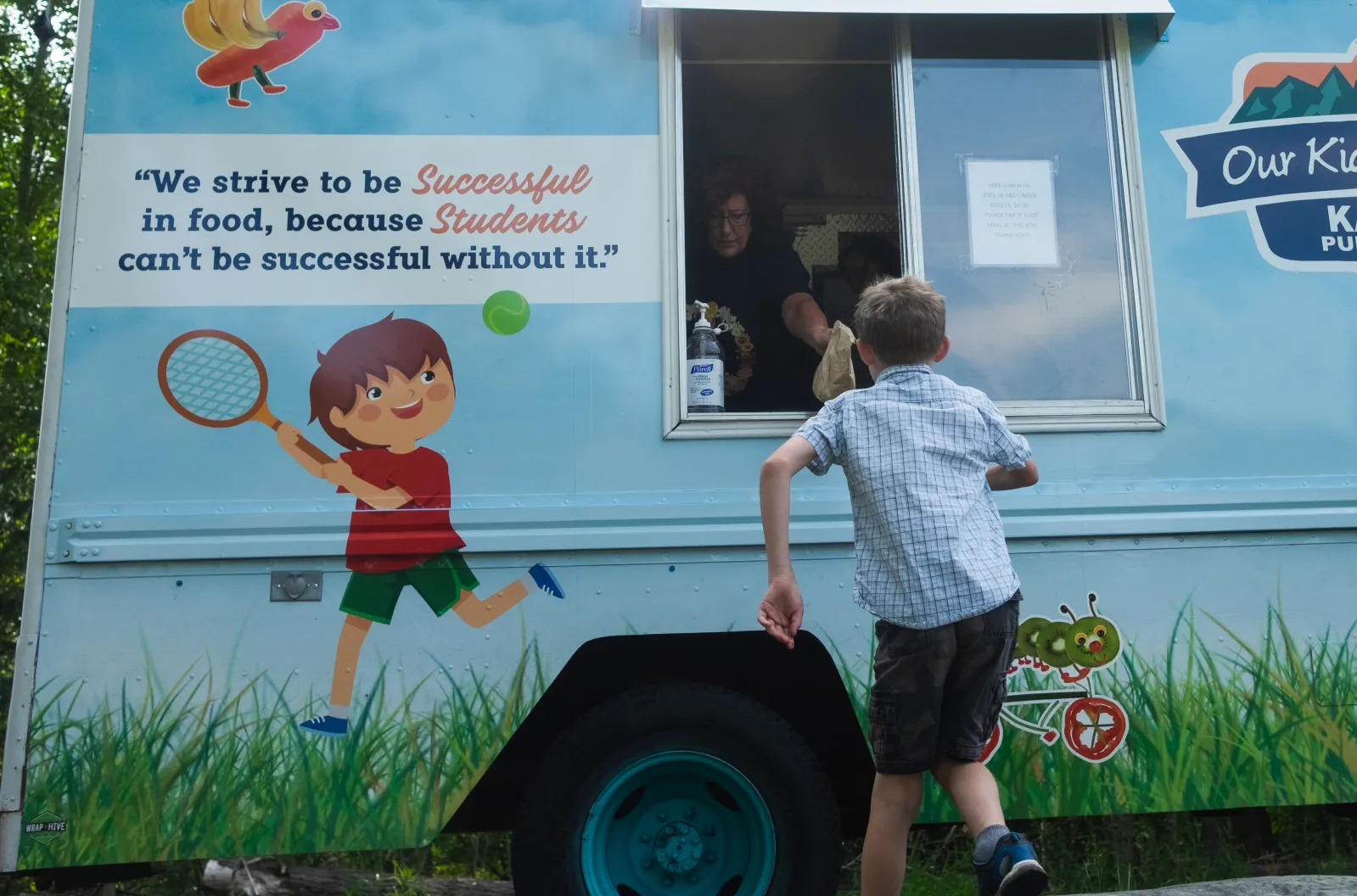 A boy runs up to a free meals truck.