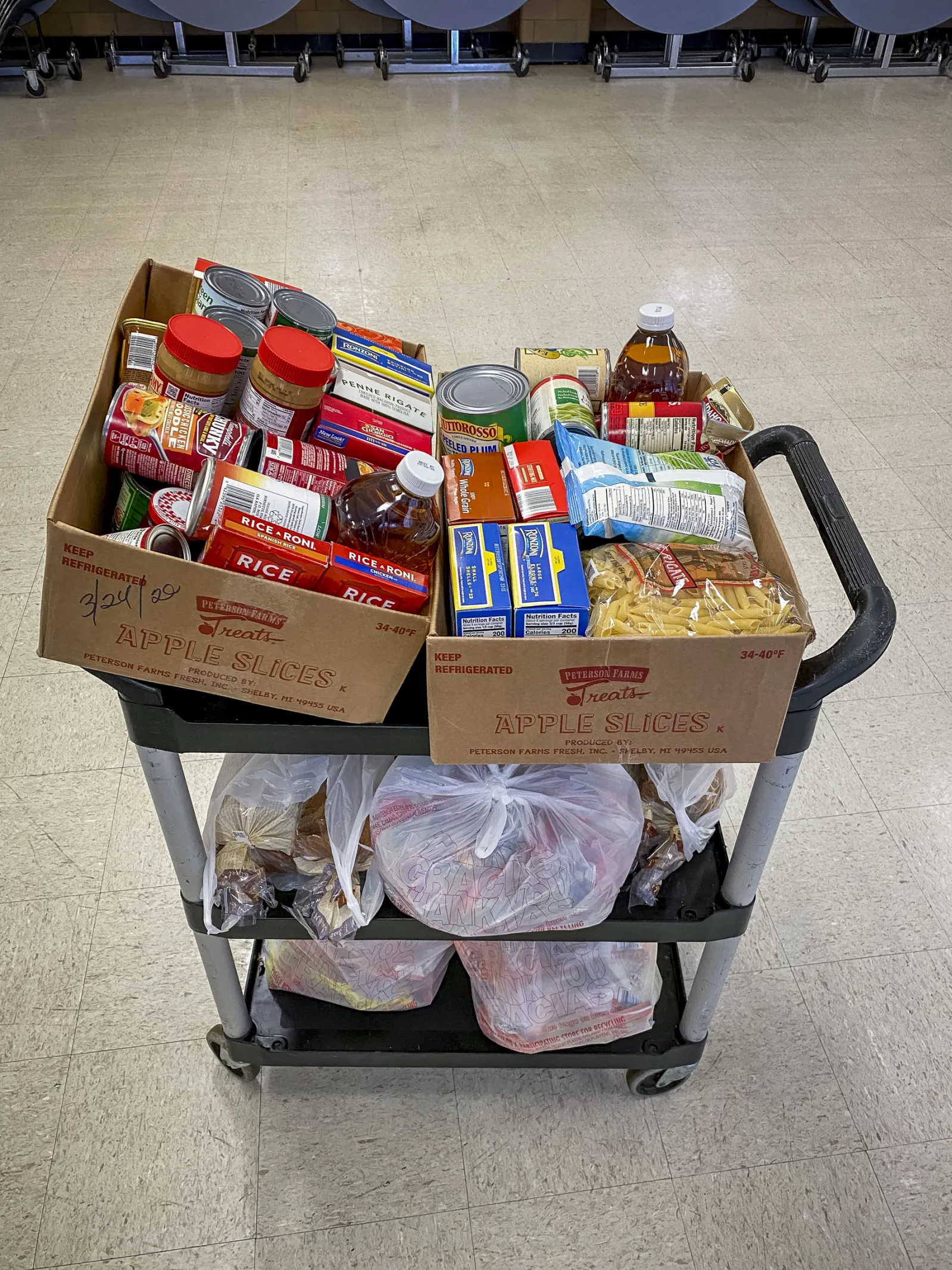 A cart is stocked with boxes of canned goods, dry pasta, juice and more for families in need.
