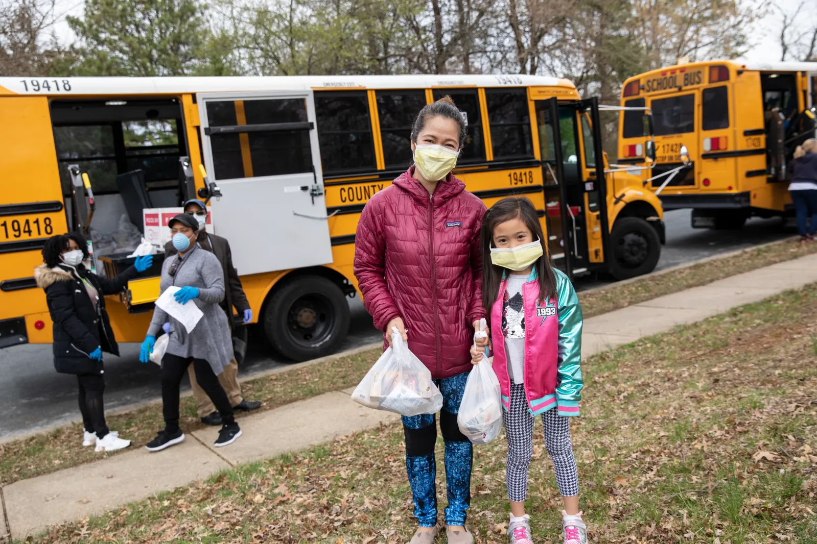 A mother and daughter pick up food at a free meals site.