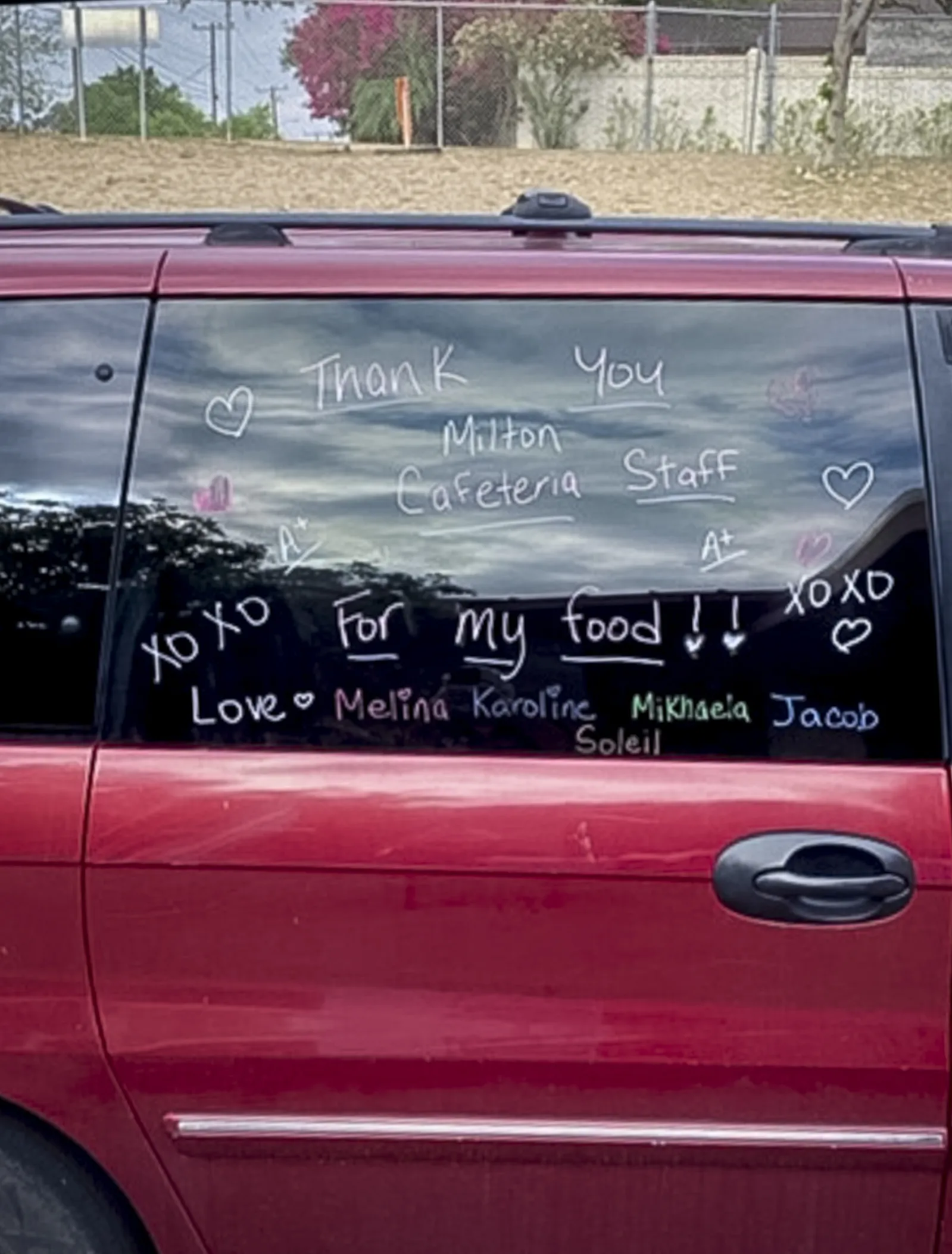 A car window has thank you notes written on it from a family. "Thank you for my food."