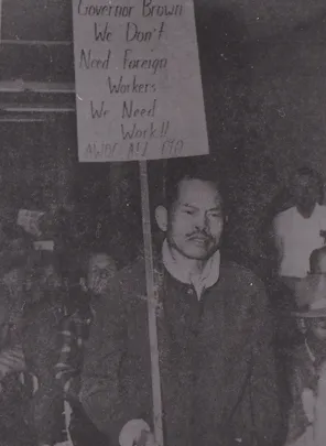 Black and whit picture, man with moustache holding sign