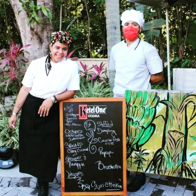 Two people wearing masks in front of food sign