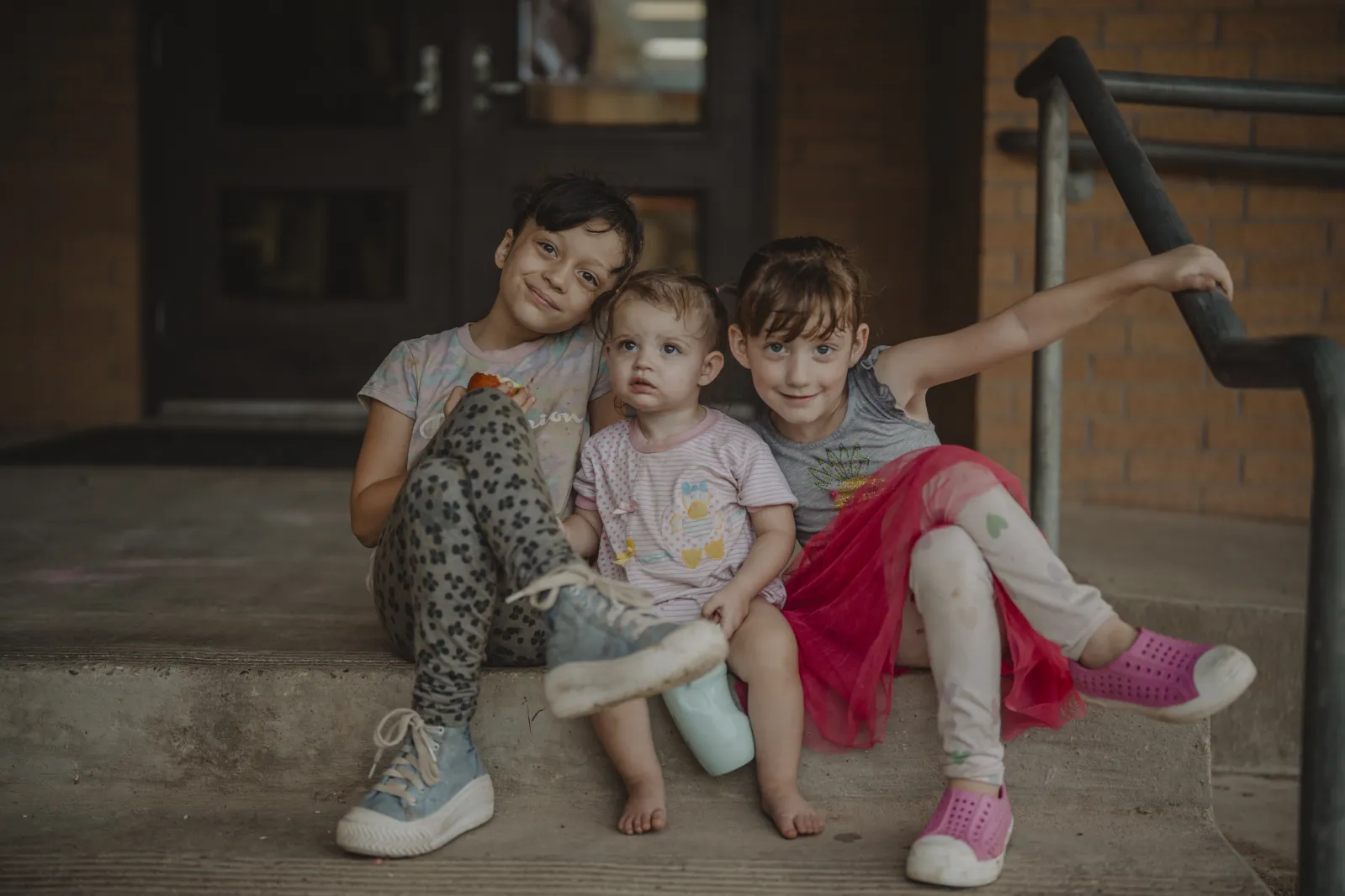 Portait of three kids sitting on stoop