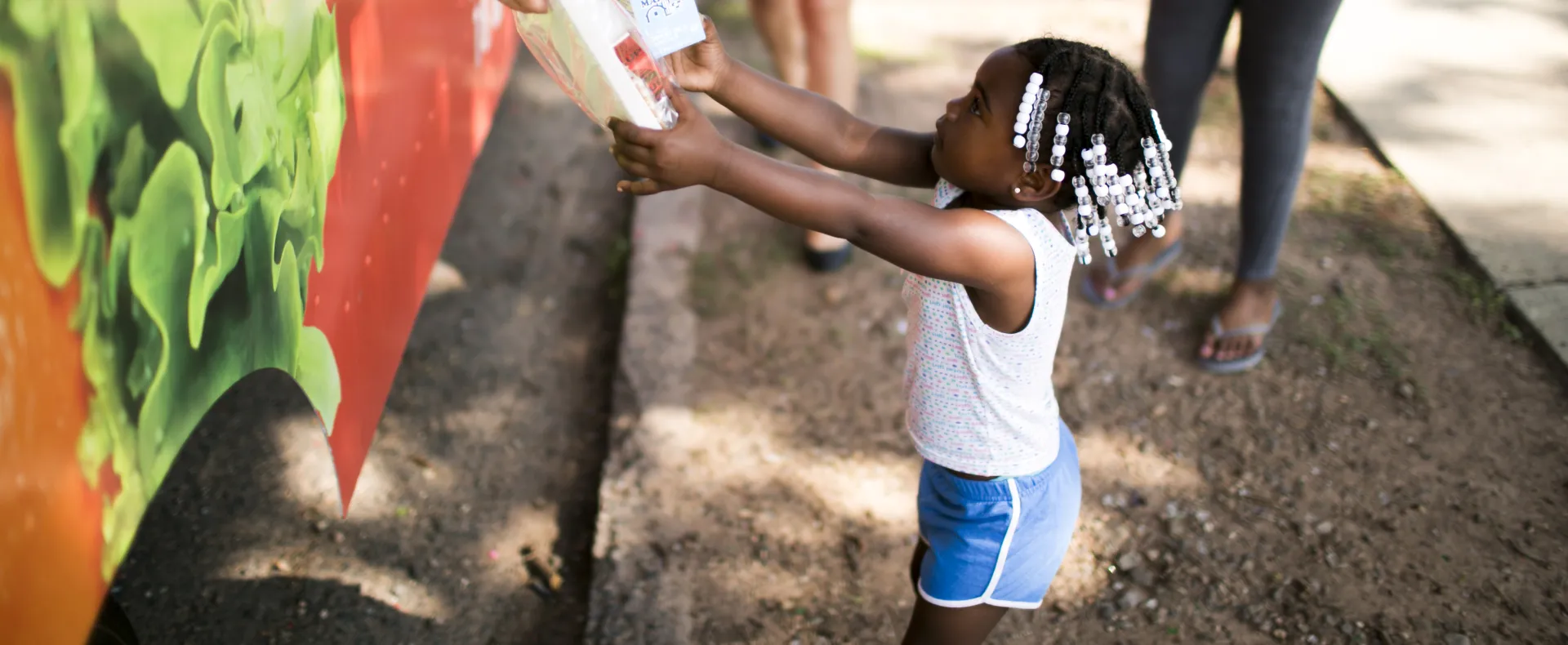 Girl reaching for meal from summer meals food truck