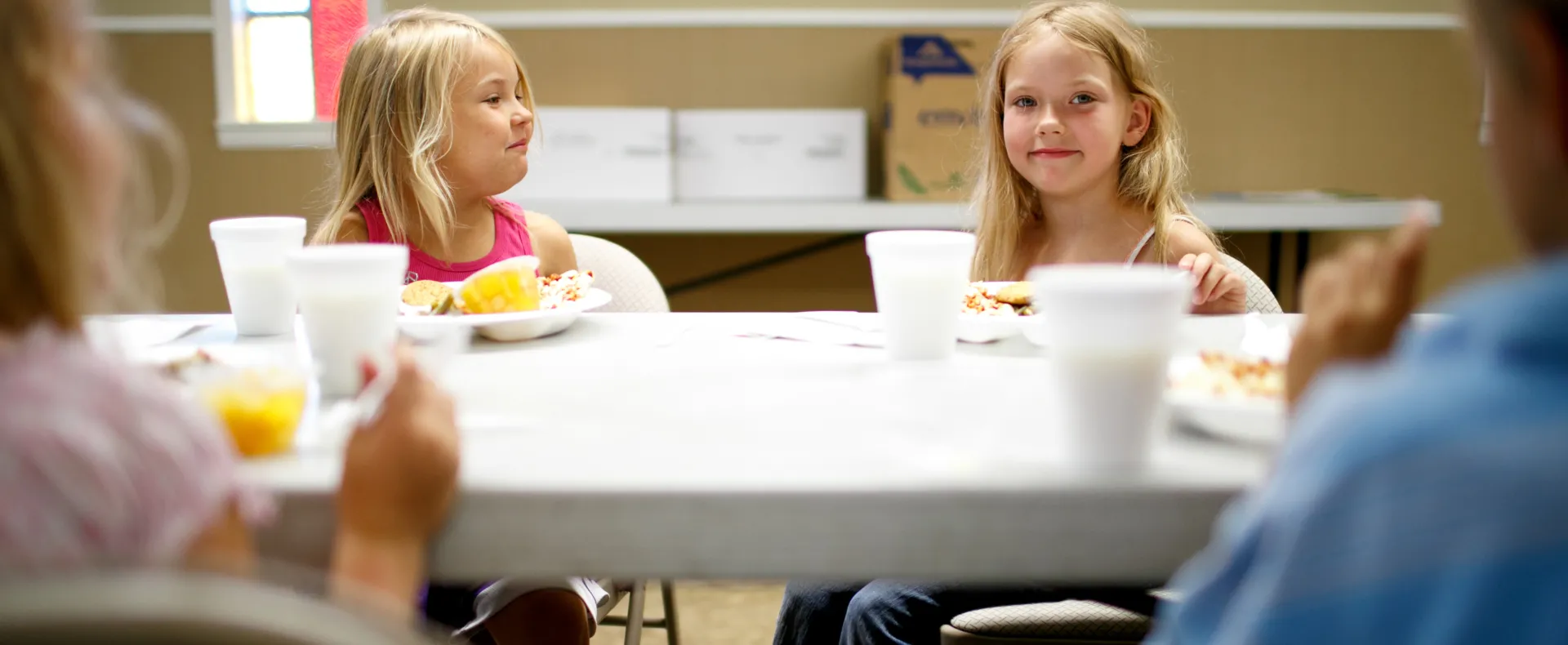 Two girls sitting at a fold out table eating and smiling