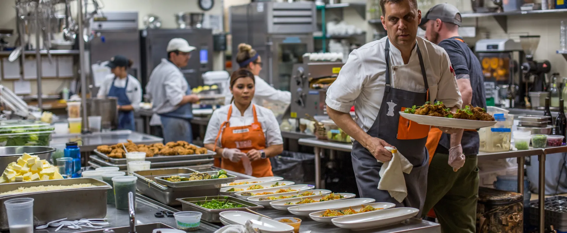 Chefs wearing No Kid Hungry aprons in a busy kitchen
