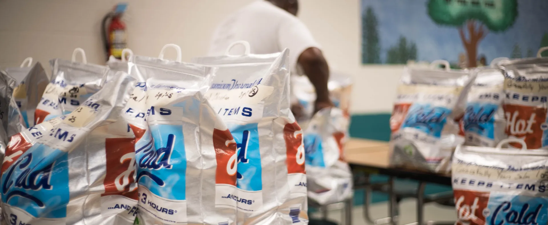 A man packs meal cooler bags for distribution.