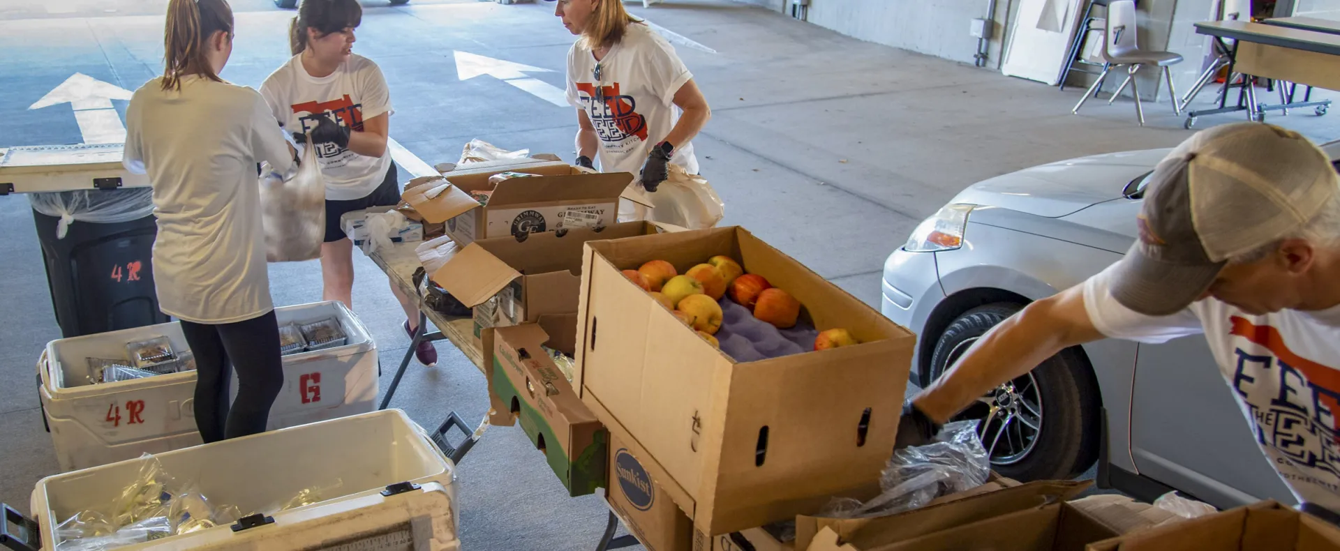 Workers pack produce into bags for cars.