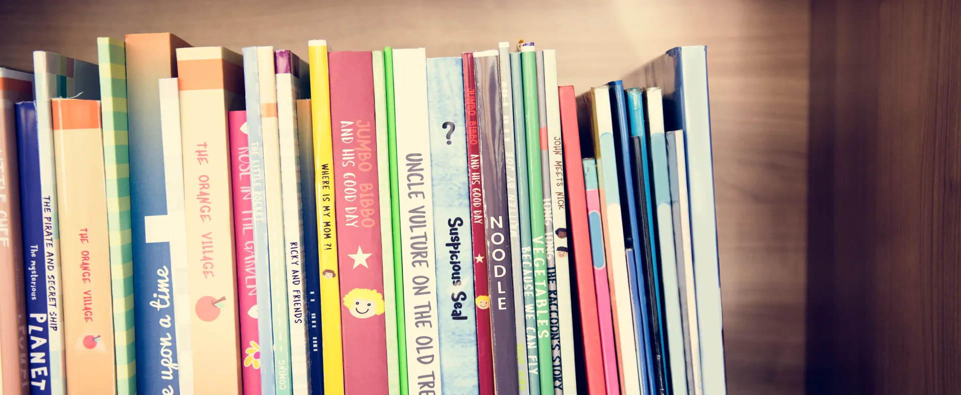 Children's books sit side-by-side each other on a shelf.