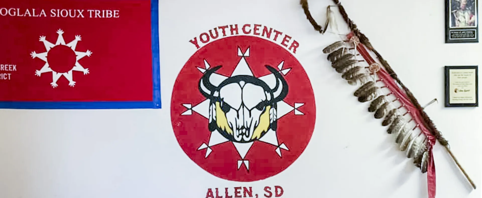 A flag and bison skull logo mark the white wall of the Lakota's Youth Center in Allen, South Dakota.