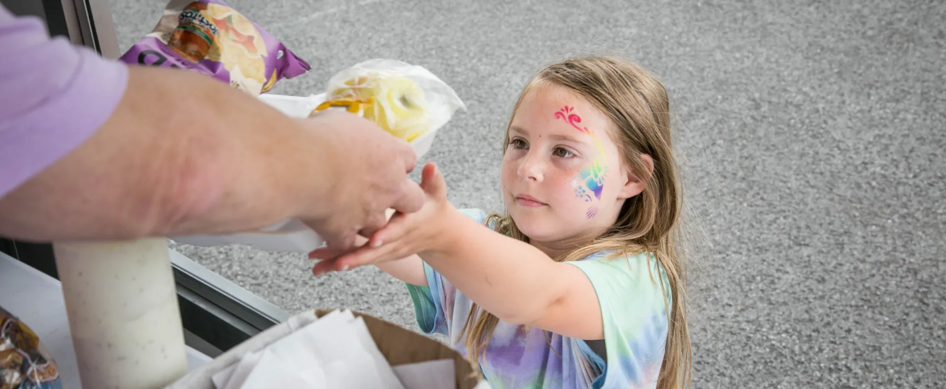 Little girl receives food from a summer meal site