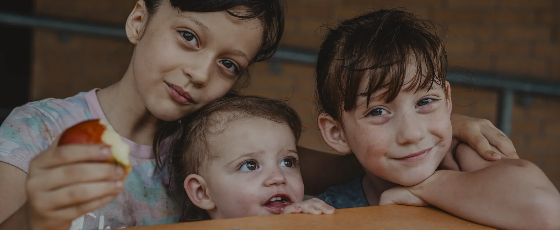 Smiling kids leaning against table
