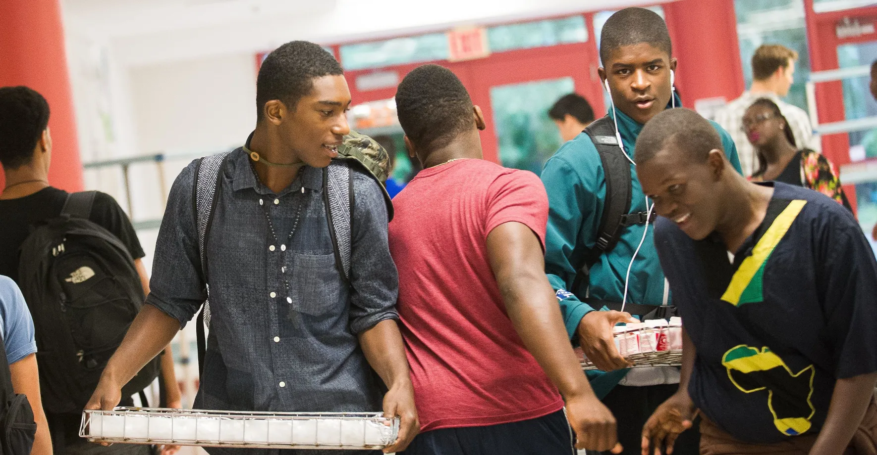 A group of students is in the hallway with trays