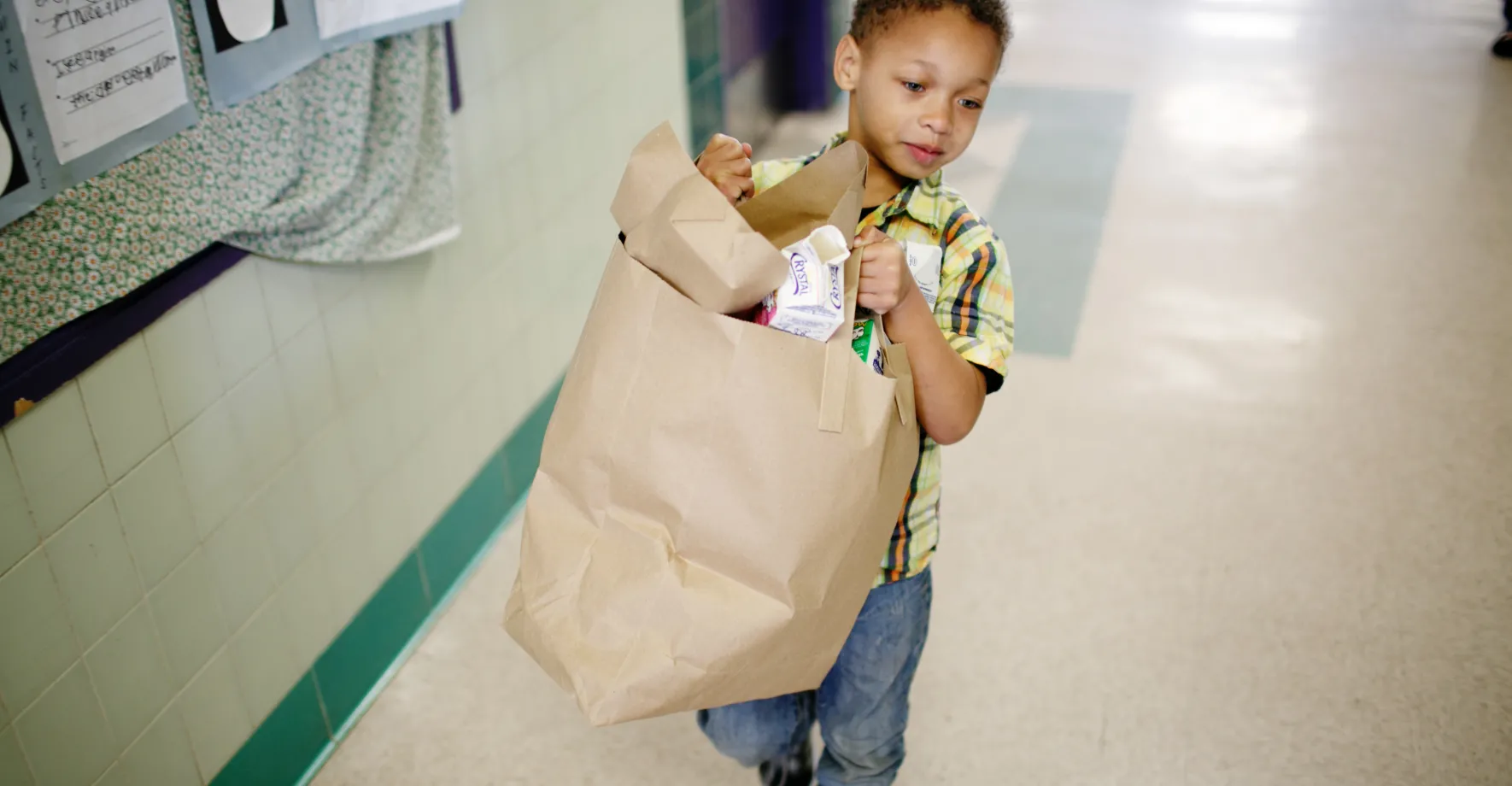 Little boy carrying trash away after classroom breakfast