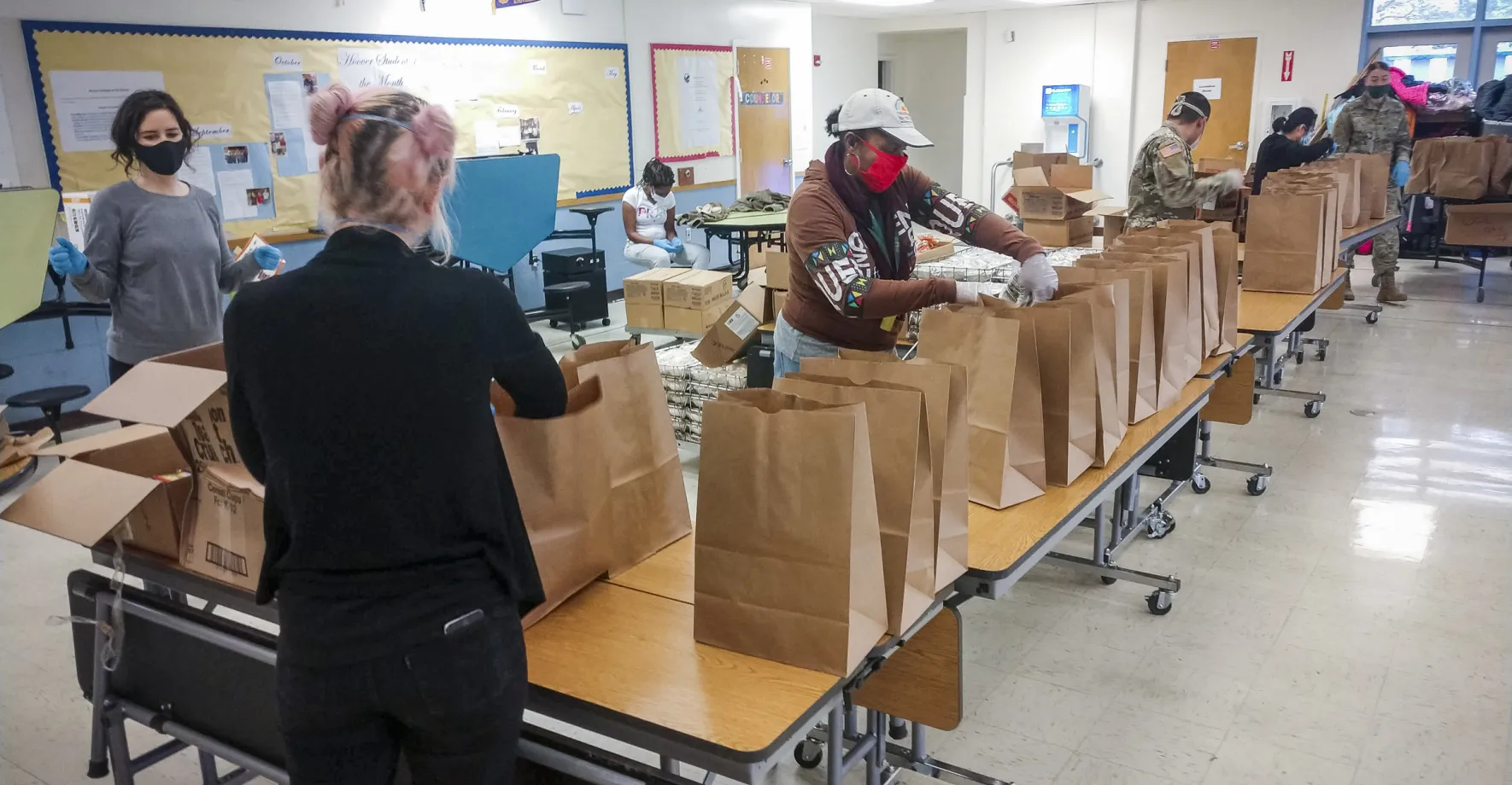 Volunteers with the Oakland Unified School District prepare packages at a meals site.