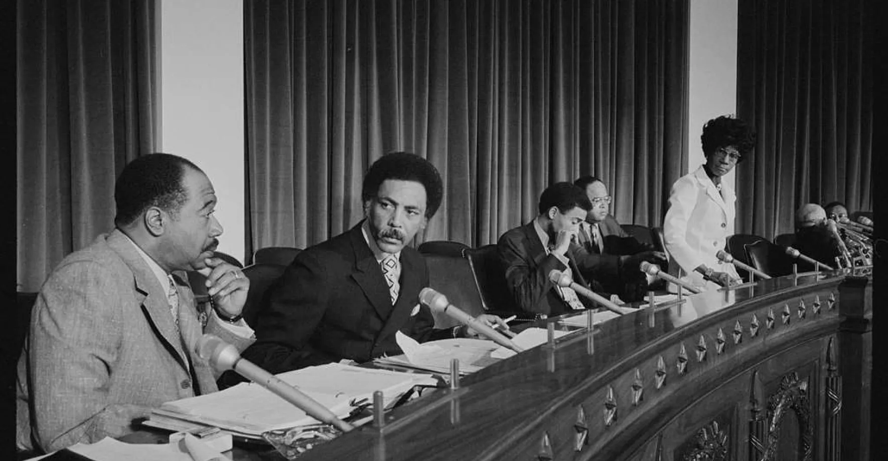 Group of Black men and a women talking by a big table