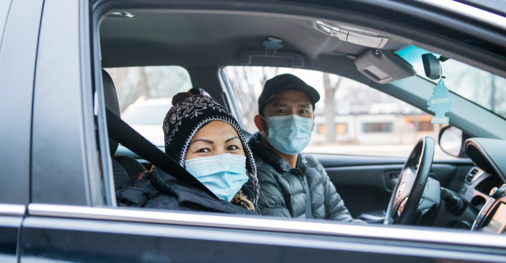 Two people in car wearing masks