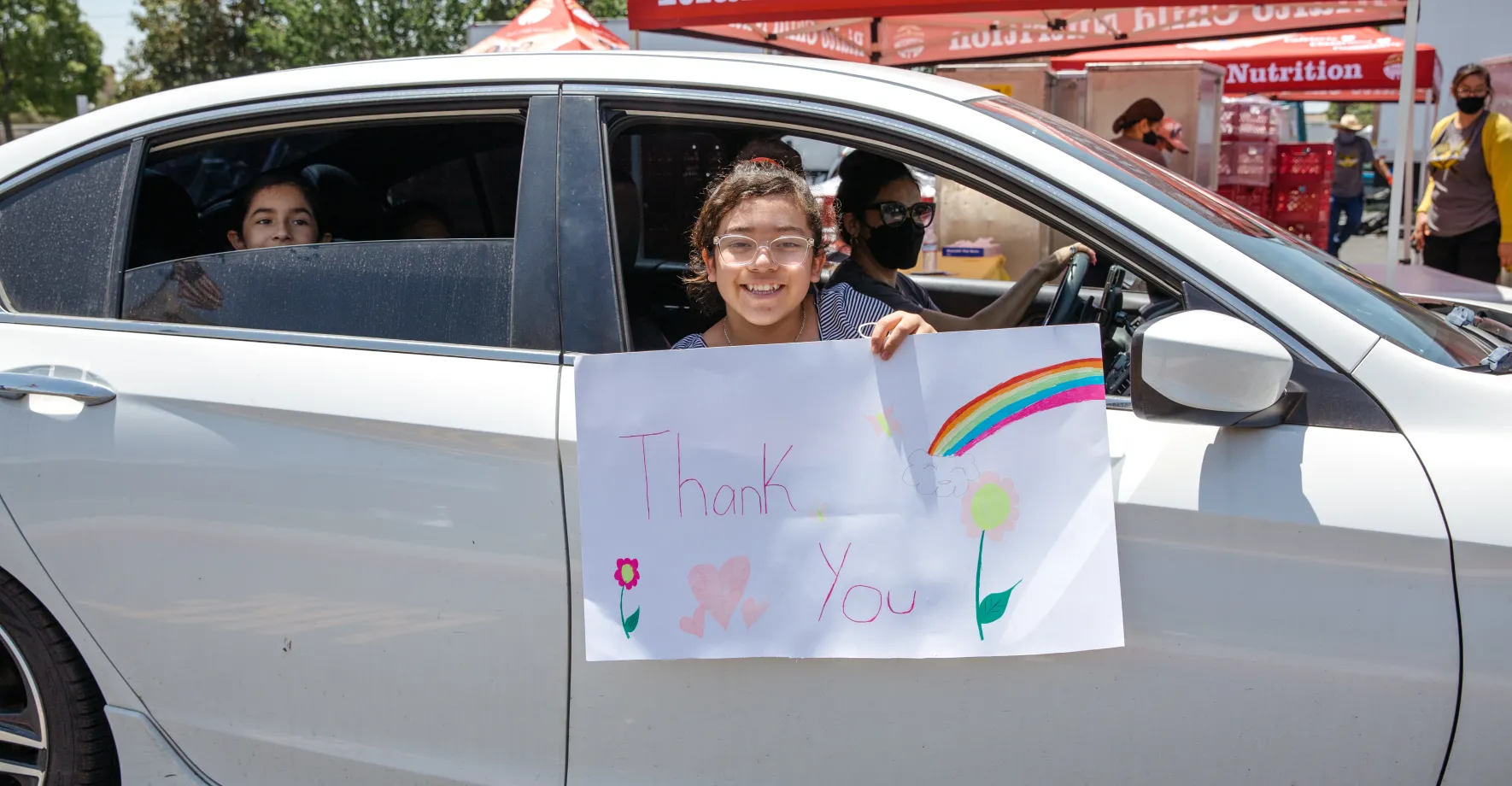 Californian kid with thank you sign in car