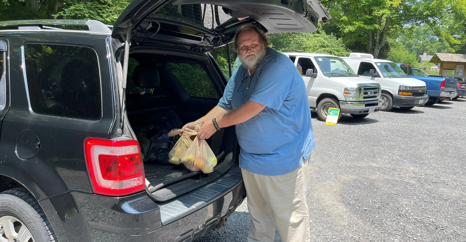 White man putting meals in trunk of car