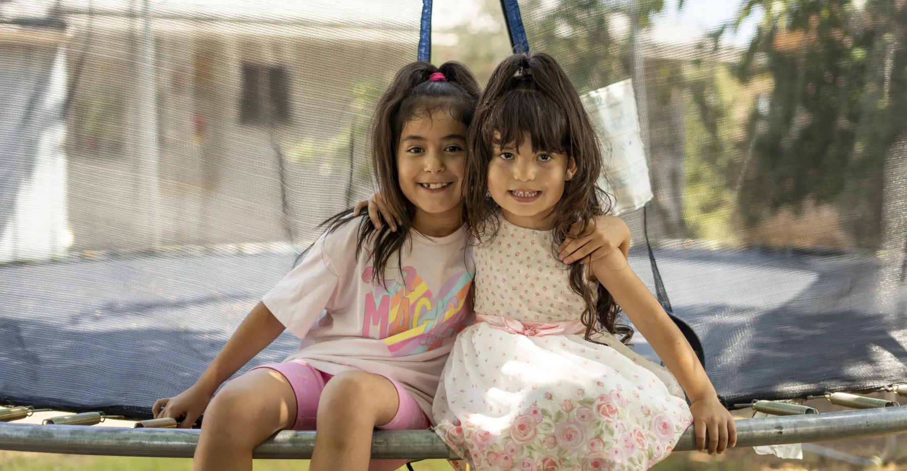 Two girls hugging on a trampoline