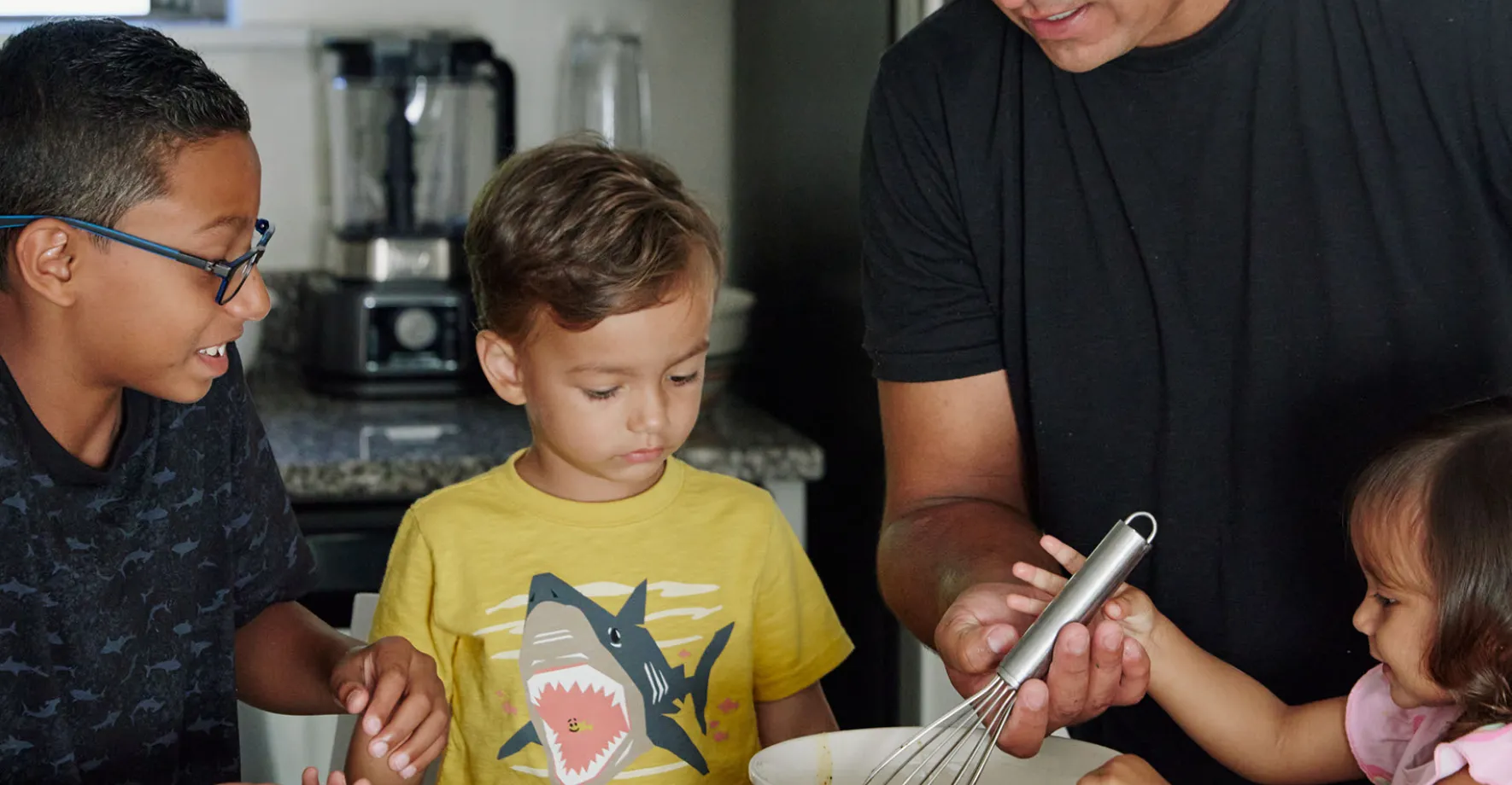 Kids in kitchen gathered around mixing bowl