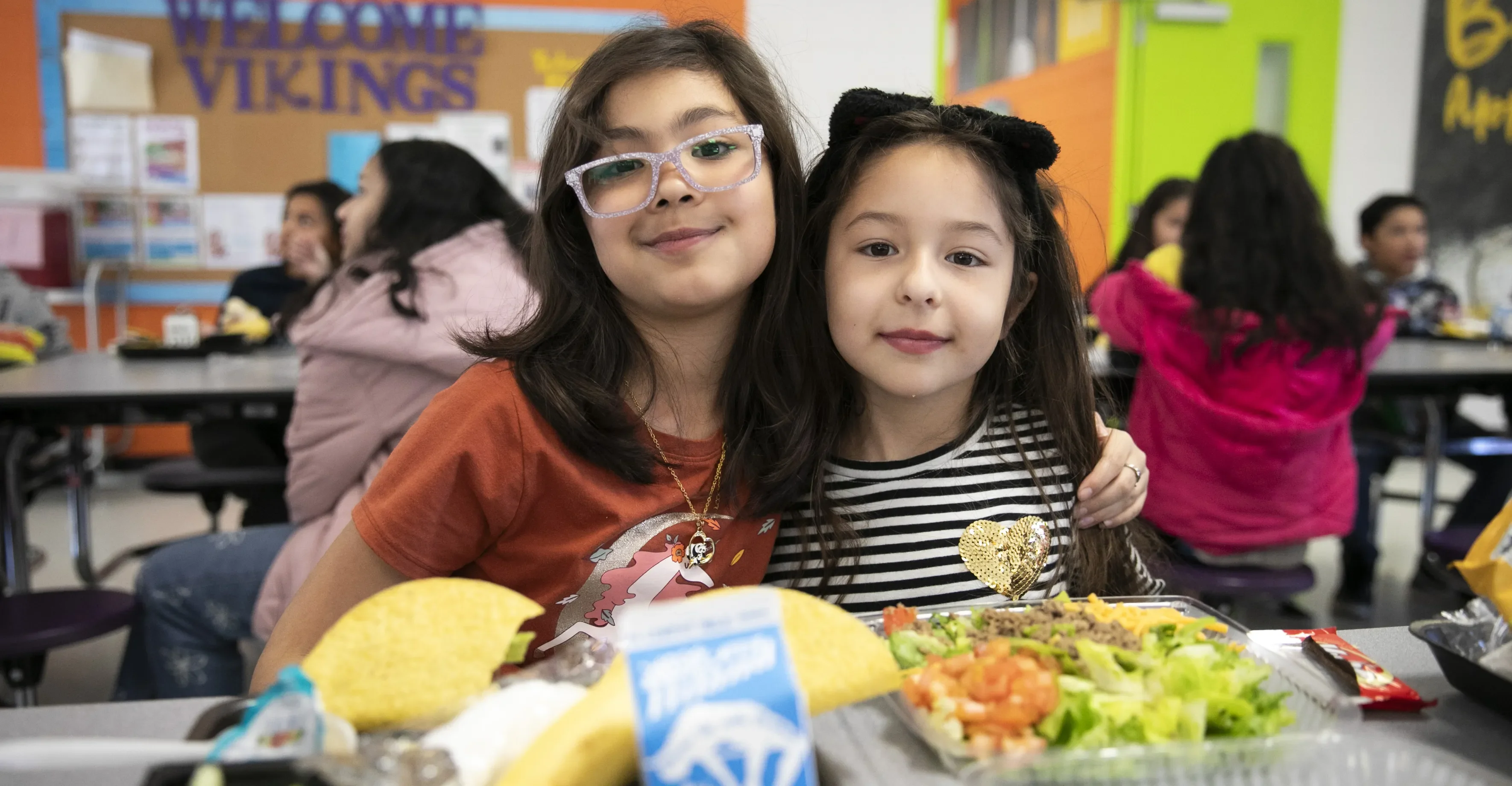 Two Latina girls posing in the cafeteria