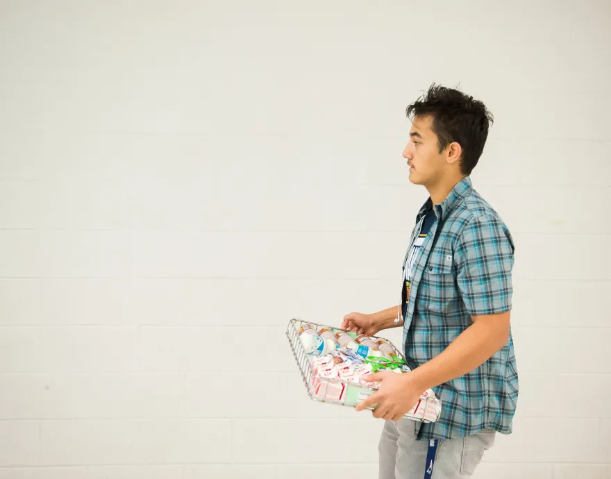 A boy walks with a tray of food