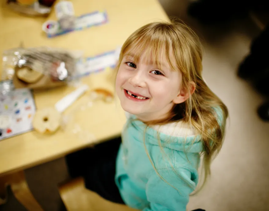 Little girl beaming and eating school breakfast