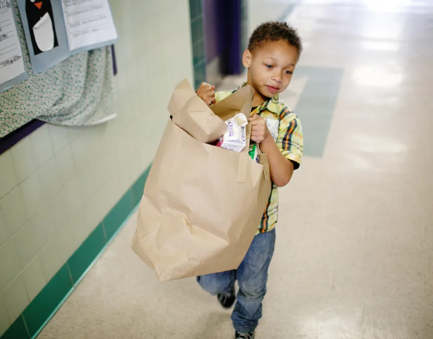 Little boy carrying trash away after classroom breakfast