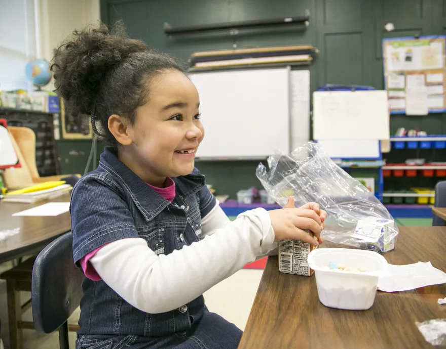 excited girl eating breakfast in her classroom