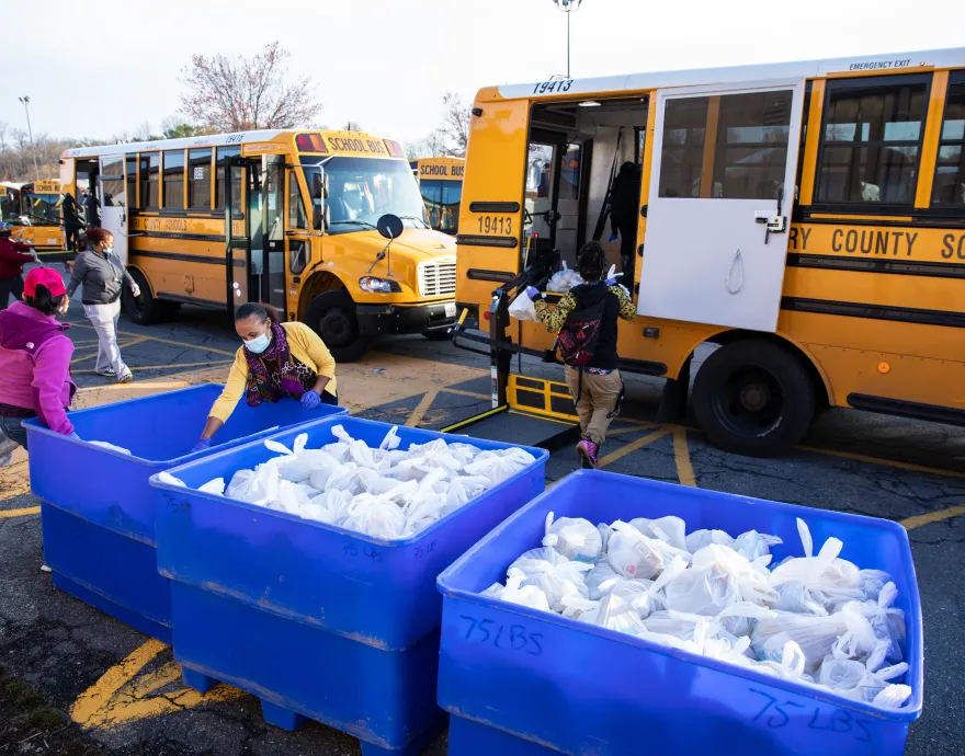 Manna Food Center staff and volunteers load school buses with food bags.