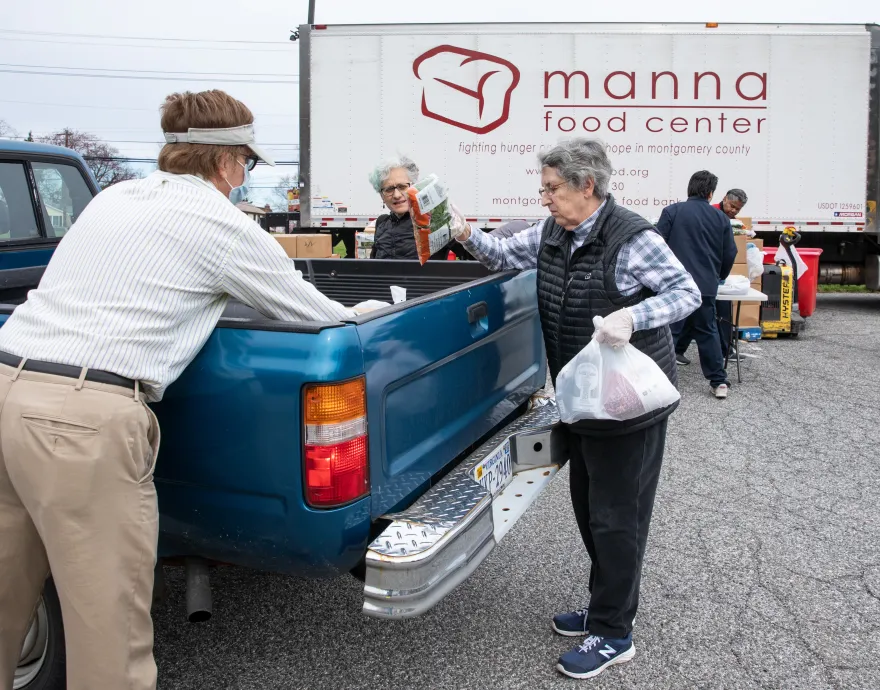 Volunteers place food bags in the bed of a truck.