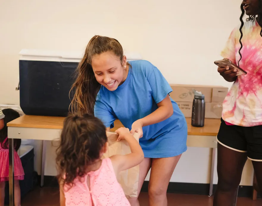 Girl passing out food to younger girl