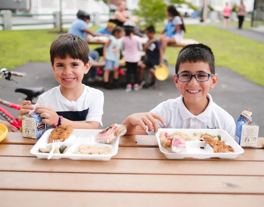 two kids eating a lunch outside