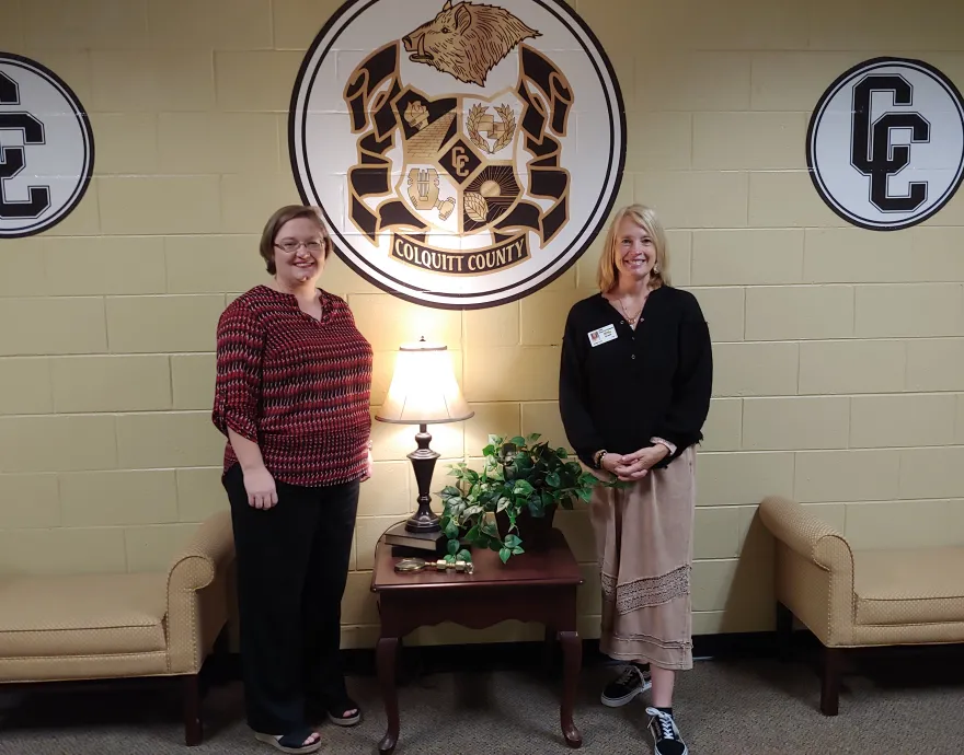 Women posing in front of school logo