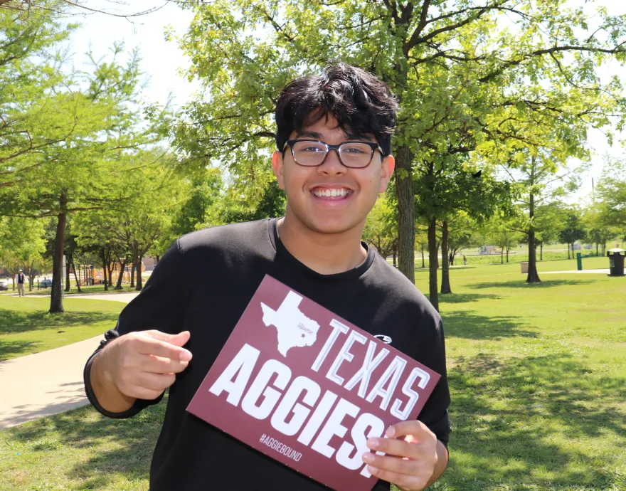 Young man holding Texas Aggies sign