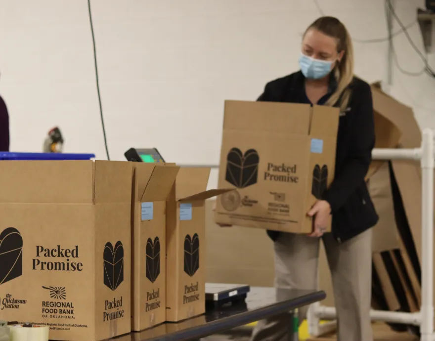 Woman carrying box that says packed promise