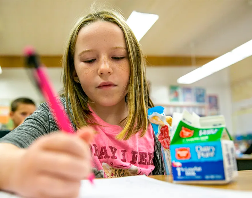 Girl at school writing with a pencil