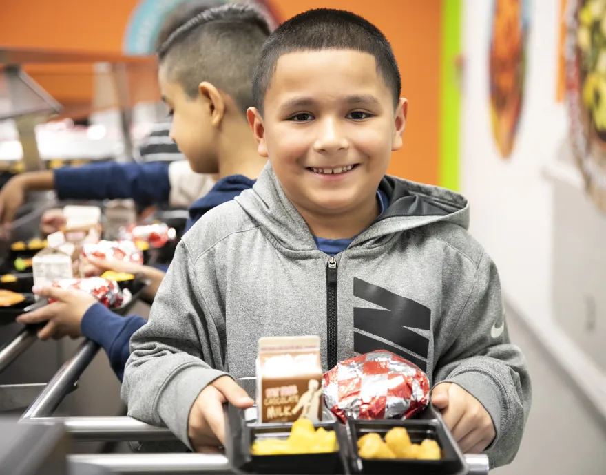 Smiling kid holding school lunch tray