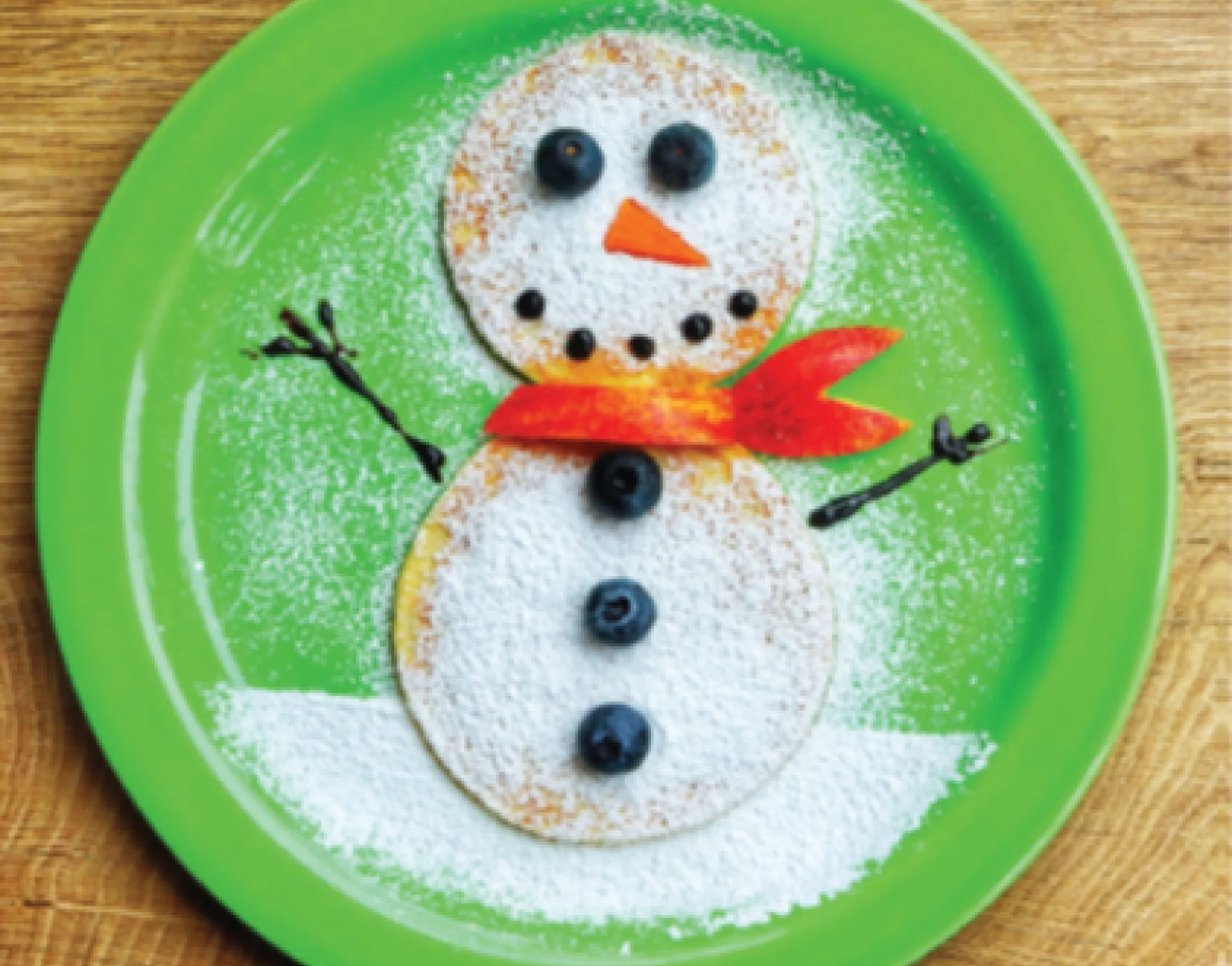 Snowman-shaped pancakes on green plate