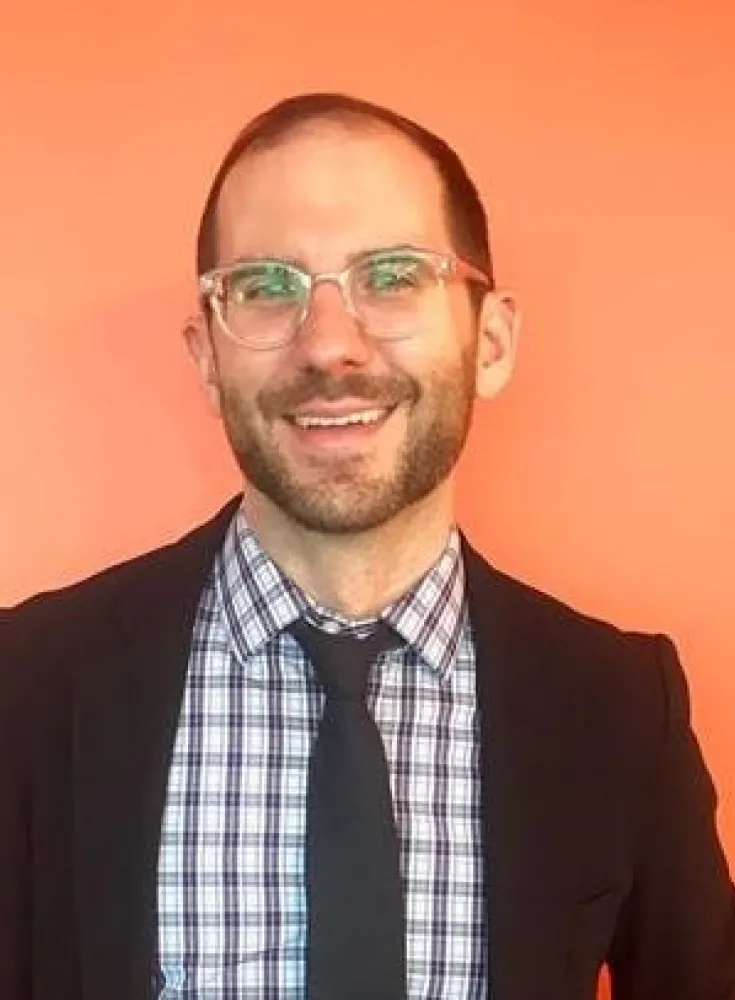 Young white man with glasses and suit. Orange background