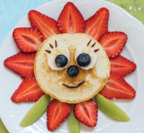 Flower-shaped pancake decorated with strawberries, blueberries, and bananas