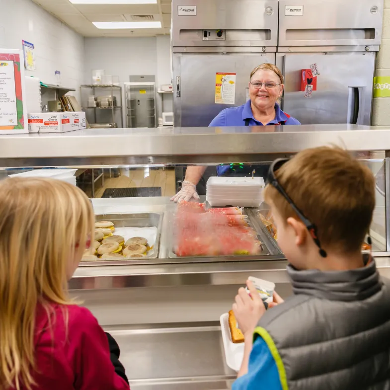 cafeteria worker smiling at kids