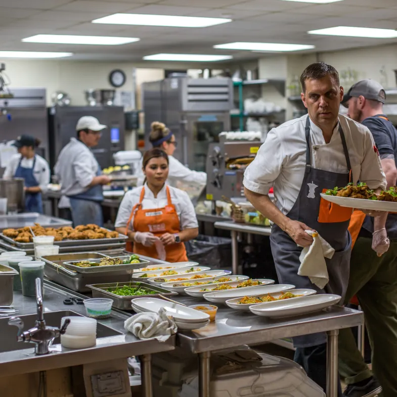 Chefs wearing No Kid Hungry aprons in a busy kitchen