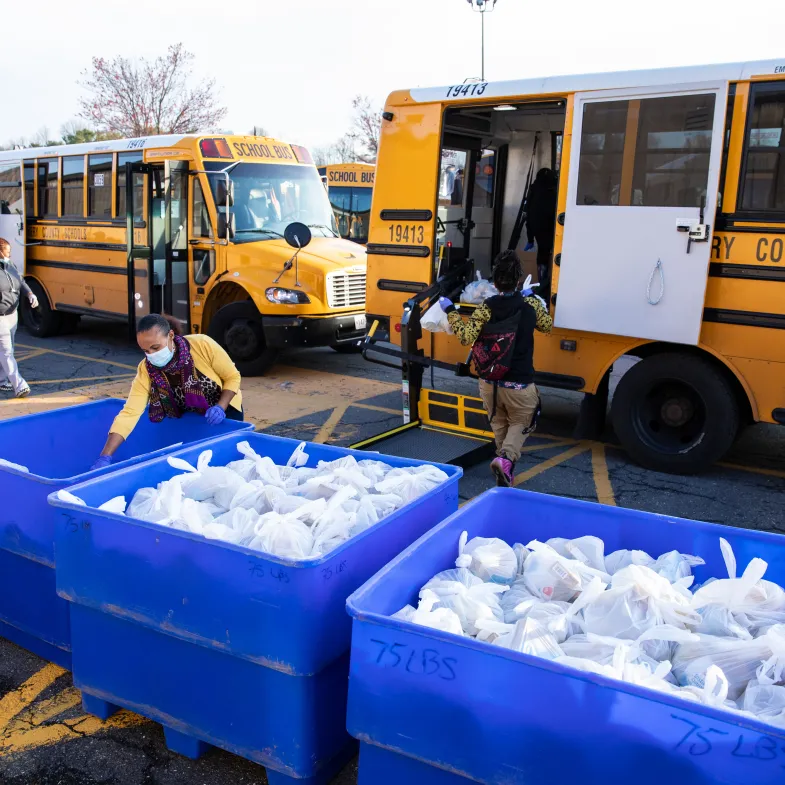 Manna Food Center staff and volunteers load school buses with food bags.