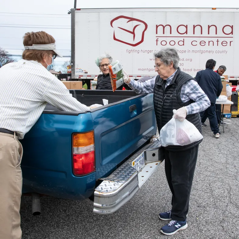 Volunteers place food bags in the bed of a truck.